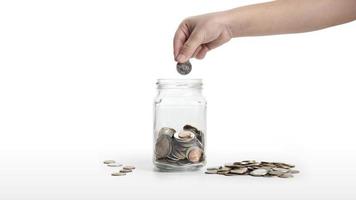 The child's hand is putting a coin into a glass jar isolated on white background. money saving concept, financial business investment, coin in glass bottle photo