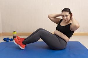 hermosa mujer asiática gorda haciendo ejercicio en casa. motivación deportiva y estilo de vida saludable. concepto deportivo, entrenamiento de resistencia, pérdida de peso saludable foto