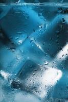 Ice cubes in a glass with crystal clear water on a blue background. Soft Selective Focus photo