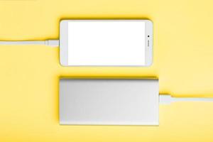 Smartphone and power bank on a yellow background isolate. photo