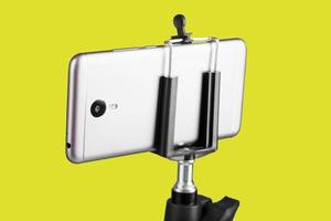 Smartphone attached to a tripod on a yellow background. photo