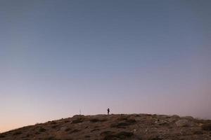 Silhouette of the person on the high rock at sunset photo