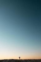 Silhouette of the person on the high rock at sunset photo