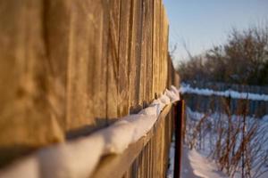 valla de jardín, acera y plantas cubiertas de nieve durante una tormenta de invierno foto