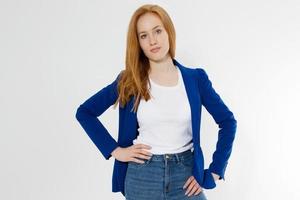 Happy red haired business woman in template blank white t shirt and stylish jacket isolated on gray background. Self career and job consulting knowledge. Young ceo entrepreneur and casual clothes photo