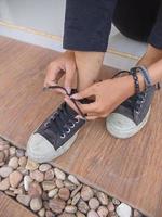 foto de manos femeninas usando y atando cordones de zapatos casuales