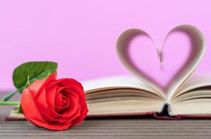 página del libro con forma de corazón curvo y rosa roja foto