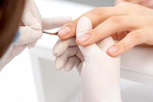 Hand of manicurist applying clear nail polish photo