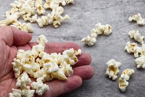 Male hand holds popcorn on grey concrete background. photo