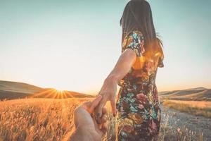 romantic couple together walk on meadow field on sunset photo