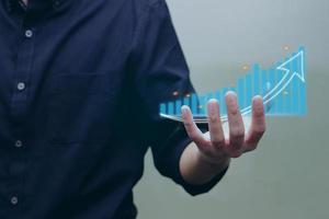 Person showing graphs and charts with rising arrows of virtual holographic statistics on his hand. photo