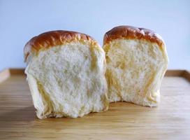 Close up showing the cross section, 2 buns of Fresh baked Japanese Hokkaido soft and fluffy milk bread, Japanese Brioche on the wooden tray with plain background, cafe mood tone color photo