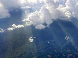 vista aérea volando sobre nubes esponjosas dramáticas y rayos solares perforando brillando a través de las nubes, paisaje nublado soleado, luz solar, viajando por aire foto