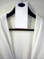 Close up a white bathrobe on a wooden hanger on the wall with blank greeting card, robe towels, hotel service photo