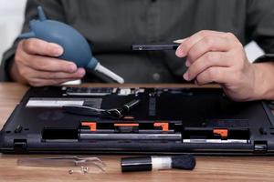 A man hold hard disk and hand air pump in repair laptop computer and tool computer repair on the table photo