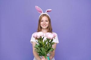 encantadora linda chica feliz con orejas de conejo rosa de pascua y ramo de primavera foto