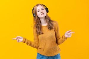 linda chica caucásica con suéter amarillo escuchando música en un teléfono móvil foto