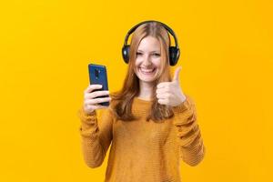 Young woman watching video clips on the phone in wired headphones in casual photo