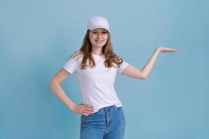 Cheerful young caucasian lady pointing at free space isolated on blue studio photo