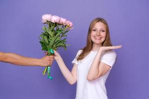 hermosa joven está emocionada de recibir un ramo de peonías para el día de la mujer foto