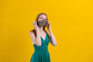 Woman in stylish outfit with designer protective face mask, green dress posing photo