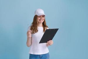 Delivery woman writing document isolated on blue background in white t-shirt photo