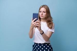 Young beautiful caucasian woman looks confused on mobile phone, she is texting photo