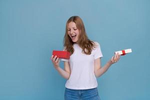 Surprised young caucasian woman holding red gift box and shocked with open photo