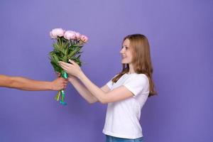 Gorgeous young lady is excited to receive bouquet peonies for women's day photo