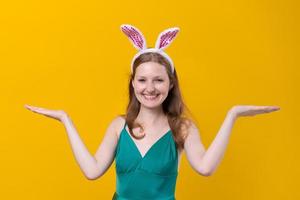 Young caucasian girl wearing bunny ears on yellow background wearing green photo