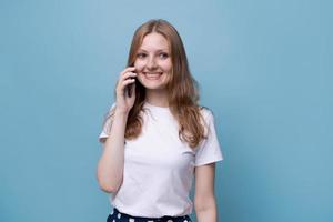 Studio portrait cheerful young woman having pleasant mobile conversation using photo