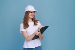 Delivery woman writing document isolated on blue background in white t-shirt photo