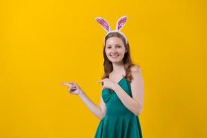 Young caucasian girl wearing bunny ears on yellow background wearing green photo