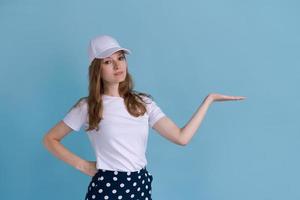 Excited young caucasian woman pointing aside at copy space on blue background photo