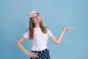 Cheerful young caucasian lady pointing at free space isolated on blue studio photo