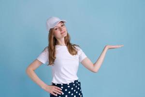 alegre joven dama caucásica apuntando al espacio libre aislado en el estudio azul foto