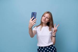 Portrait happy friendly young caucasian girl in white t-shirt on blue photo