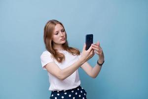 A young woman vlogger with a surprised face takes a picture of herself on the photo