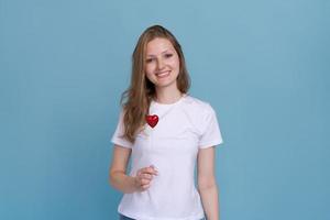 Valentine's day, girl on a blue background holds heart. Blonde smiles photo