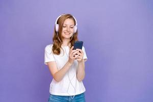 Young woman watching video clips on the phone in wired headphones in casual photo