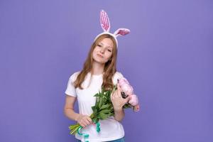 Smiling girl in rabbit ears on her head on purple studio background in white photo