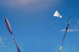 raqueta de bádminton y volante blanco sobre fondo de cielo nublado. concepto jugando al bádminton al aire libre. foto