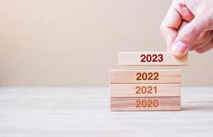 2023 block over 2022 and 2021 wooden building on table background. Business planning, Risk Management, Resolution, strategy, solution, goal, New Year New You and happy holiday concepts photo