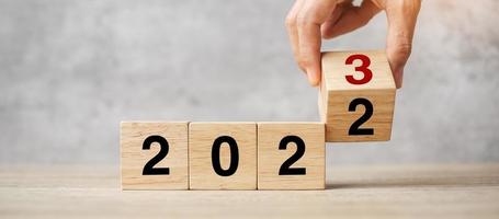hand flipping block 2022 to 2023 text on table. Resolution, strategy, plan, goal, motivation, reboot, business and New Year holiday concepts photo