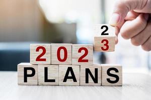 hand flipping block 2022 to 2023 PLAN text on table. Resolution, strategy, goal, motivation, reboot, business and New Year holiday concepts photo