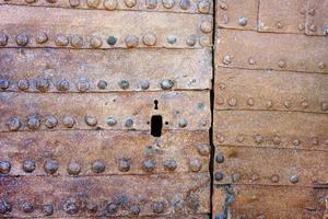 Texture of an ancient rusty iron door with rivets and keyhole photo