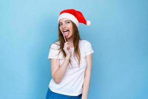 Christmas woman. Beauty model girl in santa claus hat with red lips and xmas photo