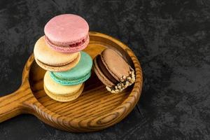 Macaroons stacked on a dark background. Delicious French cuisine dessert creatively decorated