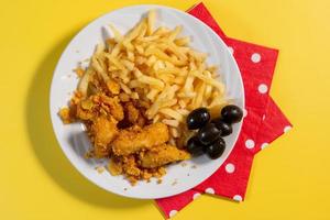 nuggets de pollo con salsa en un plato con papas fritas y oliv foto