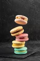 Macaroons stacked on a dark background. Delicious French cuisine dessert creatively decorated